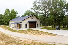 a small white barn with a black roof