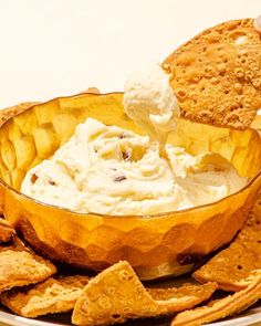 a person dipping crackers into a bowl of dip