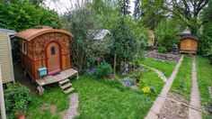 a small wooden shed sitting in the middle of a lush green yard next to trees