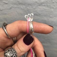 a woman's hand holding two rings with scissors attached to the ring, and another one has pink ribbon on it