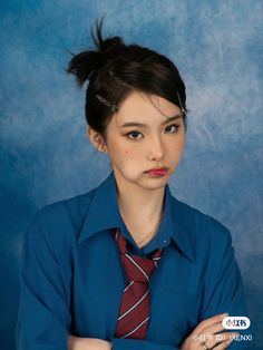 a woman in a blue shirt and tie with her arms crossed looking at the camera