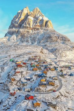 an aerial view of a small town in the mountains with snow on it and houses below