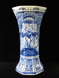 a large blue and white vase sitting on top of a table next to a black background