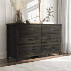 a dresser with drawers and vases on top of it in front of a window