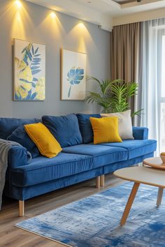 a living room with blue couches, yellow pillows and paintings on the wall above them