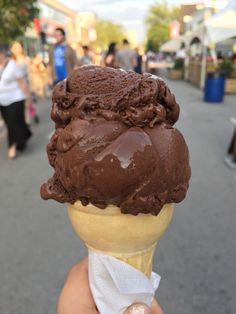 a hand holding an ice cream cone filled with chocolate