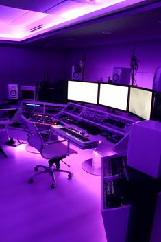 a room filled with lots of computer monitors and sound mixing equipment in it's purple lighting