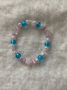 a bracelet with pink, blue and white beads on it's end is laying on a bed