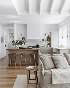 a living room and kitchen area with white walls, wood floors and an open floor plan