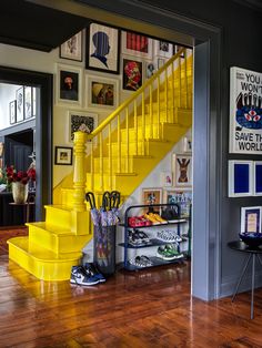 a yellow staircase in a home with pictures on the wall and wooden floors below it