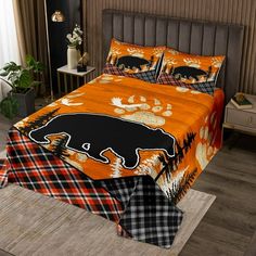 a bed with an orange and black bear comforter set on it's side