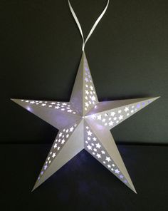 an origami star with white stars on it is lit up in the dark