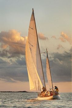 a sailboat is sailing in the ocean on a sunny day with clouds above it