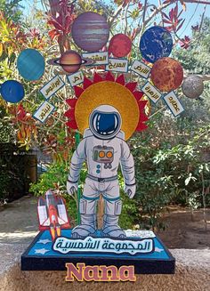 a statue of an astronaut standing in front of a tree filled with planets and sun