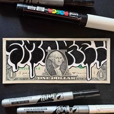 a one dollar bill with black marker pens on it next to some markers and crayons