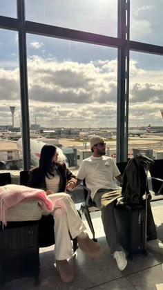 two people are sitting in an airport waiting for their luggage to be picked up from the plane