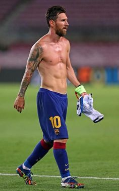 a shirtless man walking on a soccer field with his glove in his hand and the ball in his other hand