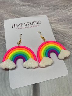 the rainbow earrings are on display in front of a white card that says home studio