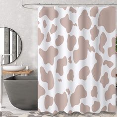 a bathroom with a bathtub, sink and shower curtain that has a cow print on it