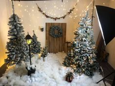 fake christmas trees are set up in front of a door with lights and wreaths