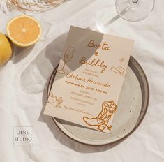 an orange and wine glass sitting on top of a plate next to a paper sign