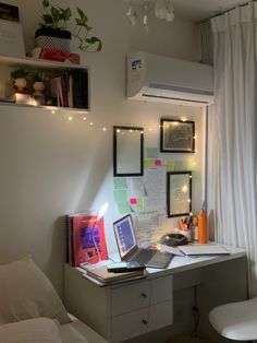 a laptop computer sitting on top of a desk next to a white chair and window