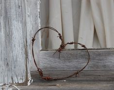 a heart - shaped piece of barbed wire sits in front of an open window