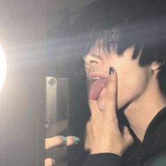 a person sticking their tongue out in front of a mirror with light shining on them