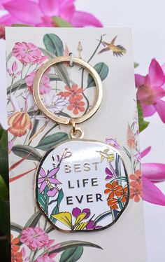 a keychain with the words best life ever on it and flowers in the background