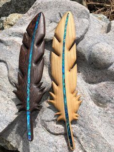 two wooden feathers sitting on top of a rock