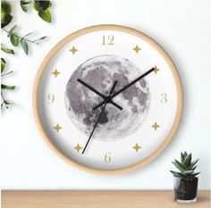 a clock with stars and the moon on it's face next to a potted plant