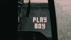 there is a sign that says play boy on the side of a bus window in the rain