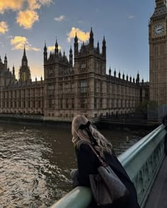 a woman standing on the edge of a bridge looking at big ben