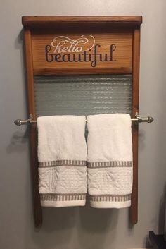 two white towels are hanging on a towel rack in a bathroom with the word hello beautiful above it