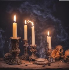 a table topped with candles and skulls on top of it's sides in front of a dark background