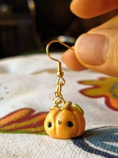 a person holding onto a tiny pumpkin charm