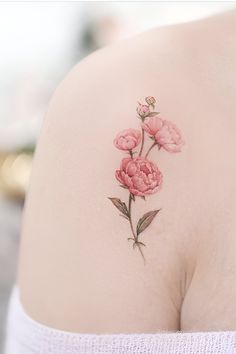 a pink flower tattoo on the back of a woman's shoulder