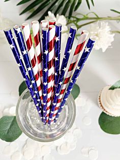 red, white and blue paper straws in a glass vase with flowers on the side