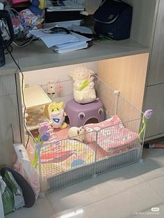 a baby crib with stuffed animals in it and other toys on the floor behind it