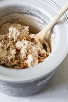 a white bowl filled with food and a wooden spoon in the cup next to it