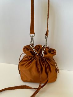 Dimensions H 28 cm/ 11 in  W 22 cm / 8.6 in D 10 cm /  3.9 in Materials Dark bronze  color Satin Fully lined in beige  color satin. Drawstring closure.  Detachable top handle and long strap. Dark bronze satin small bag. The mouth of the bag made of satin  is closed by squeezing.  The handles made of the same satin fabric are mounted on the bag with silver-colored metals. Four metal feet in silver color on the base protect the bag from dirt when placed on the floor. A special material is used bet Elegant Brown Pouch With Adjustable Strap, Elegant Handheld Pouch With Adjustable Strap, Bucket Evening Bag With Handles, Gold Bucket Bag With Adjustable Strap For Evening, Evening Gold Bucket Bag With Adjustable Strap, Brown Crossbody Bucket Bag For Evening, Evening Brown Bucket Bag With Detachable Strap, Evening Brown Crossbody Bucket Bag, Pouch Bucket Bag With Handles For Evening