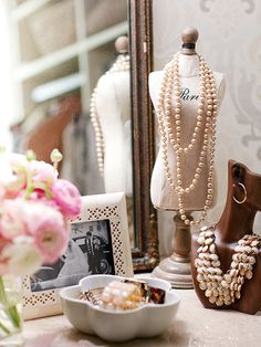 a mannequin with pearls on it next to a bowl of food and flowers