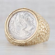 This eye catching ring features a silver coin with a side profile stamped to one side and a figural design to the other. The coin is bezel set in a nugget accented band. Please note we are unsure of the authenticity or origin of the coin. Metal: 14k Yellow Gold (stamped), 98% Silver (XRF tested) Weight: 17.9 Grams  Stamps: 14k Face Height: 22.5 mm  Rise Above Finger: 5.3 mm Band / Shank Width: 4.5 mm This ring is a size 12 1/4, but it can be resized down 2 sizes for a $20 fee or up 3 sizes for a $30 fee per size. If you would like your ring resized, please select the appropriate fee from the listing below in order to pay the sizing fee: https://www.etsy.com/listing/781388346/ring-sizing-service-fee Each piece is thoroughly examined and refinished as needed by our professional jewelers, gra Antique Engraved Coin Signet Ring, Antique Coin-shape Engraved Signet Ring, Antique Coin Shaped Engraved Signet Ring, Classic Collectible Coin Rings, White Gold Intaglio Signet Ring, White Gold Signet Ring With Intaglio, Antique Collectible Coin Rings, 14k Gold Coin-shaped Rings, Heirloom Coin Shaped Hallmarked Rings