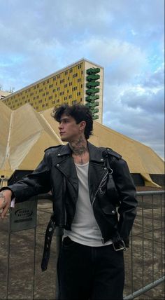 a man in black leather jacket standing next to a fence