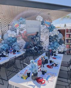 an outdoor party setup with balloons, decorations and tables in the shape of spiderman