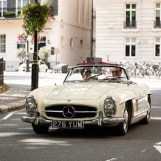 a man driving a classic car down the street