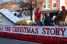 people are riding in a float down the street with christmas decorations on it's side