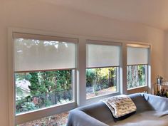 a living room filled with furniture and two windows covered in blind shades over the top of them