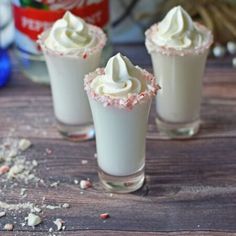 three glasses filled with whipped cream and sprinkles on top of a wooden table