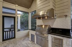 an outdoor kitchen with stainless steel appliances and black counter tops, along with sliding glass doors